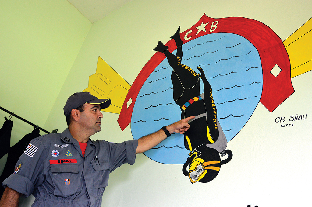 TEMA — O bombeiro Marcos Alexandre Simili mostra seu mais recente desenho, numa sala com equipamentos para salvamento aquático